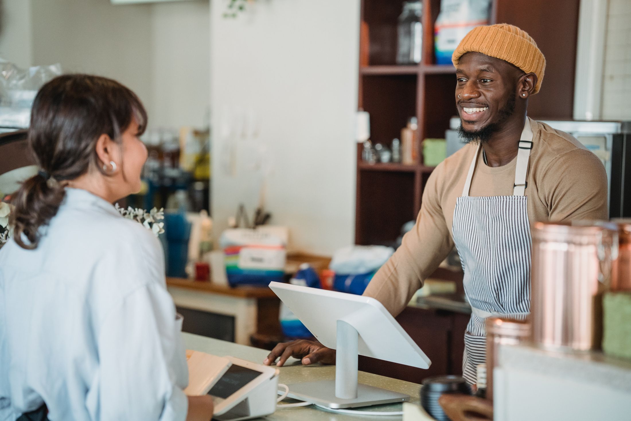 A barista welcoming a customer at a neighborhood café